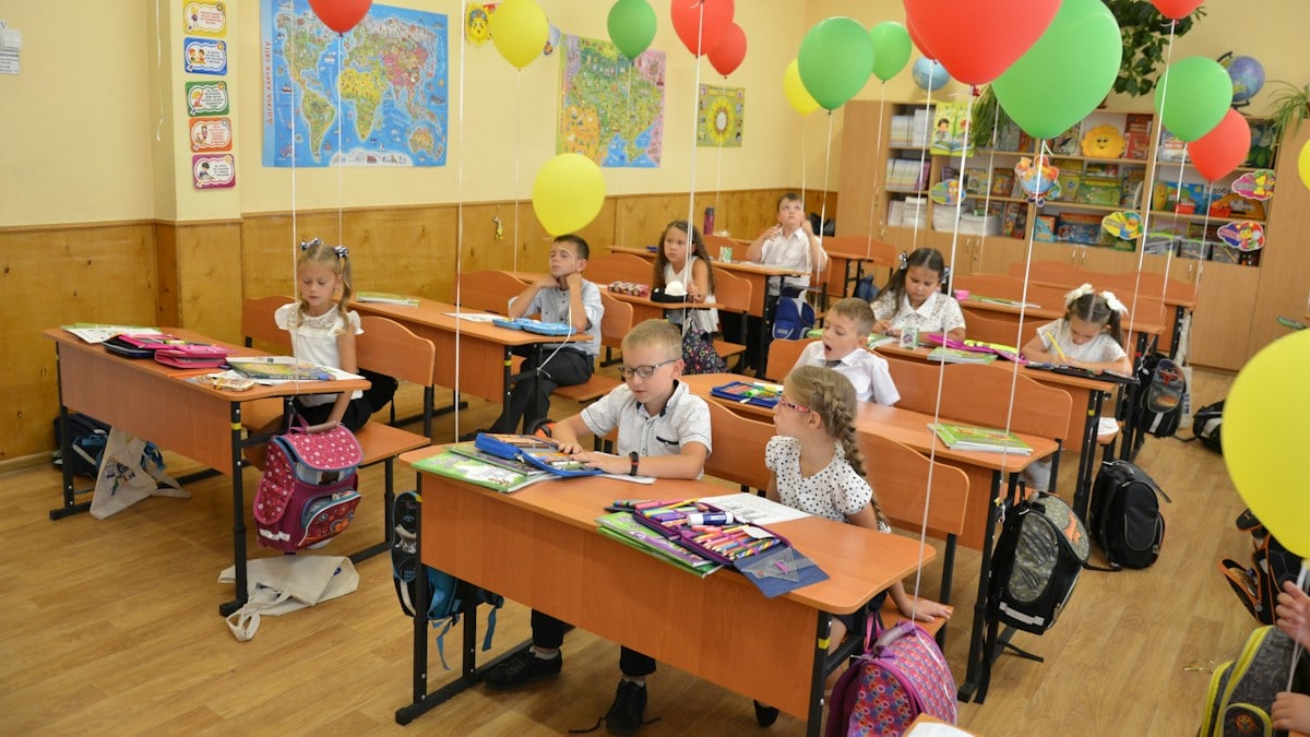 Two diverse elementary school children classmates studying together at desk